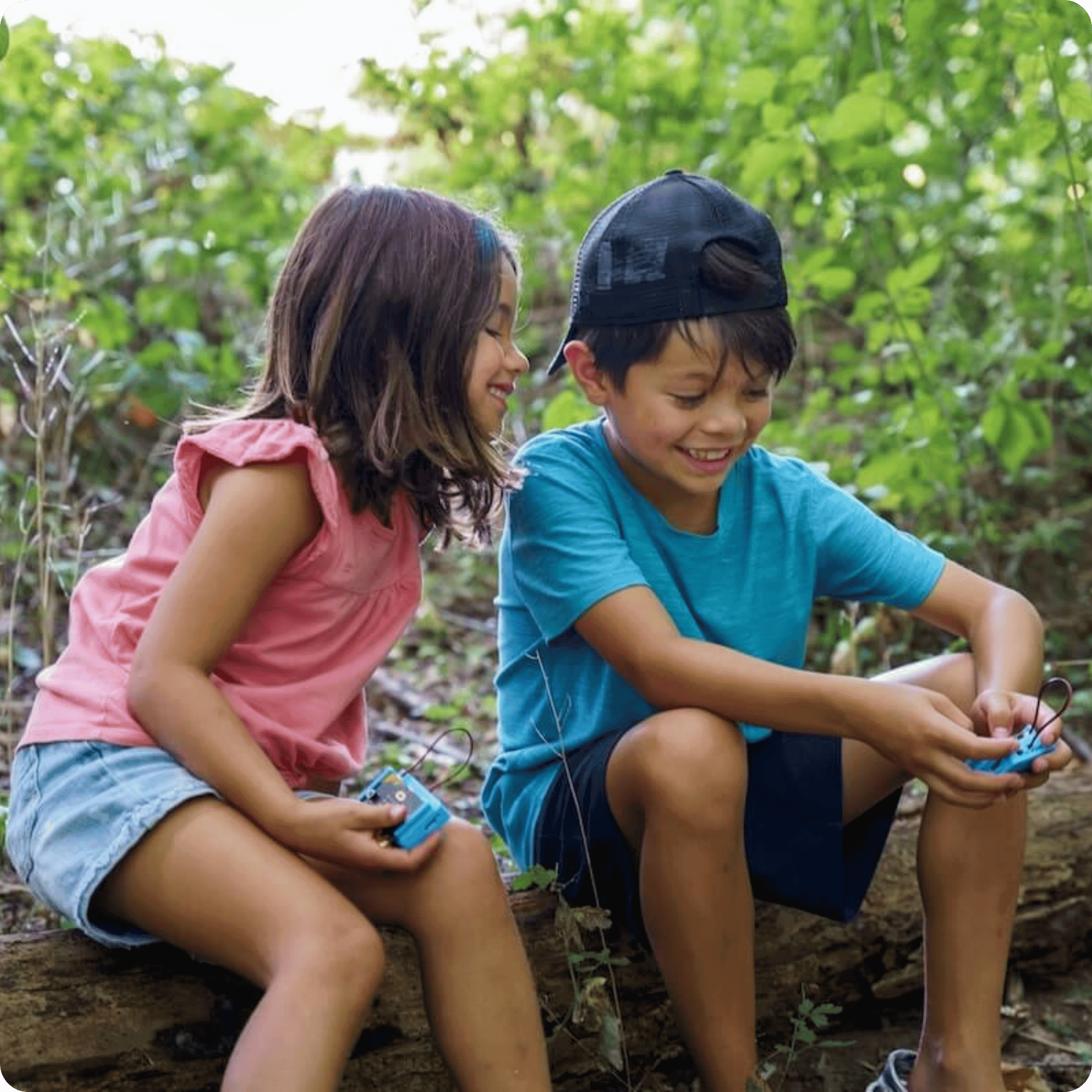 Kids sitting on a log with CHARGE for micro:bit collecting data