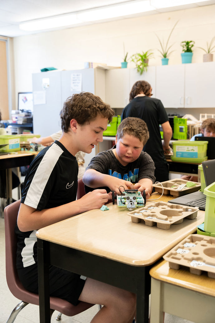 Two students assembling a circuit board module from a STEM engineering kit at a classroom table | Forward Education