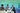Three educators collaborating on coding project displayed across multiple laptop screens in classroom | Forward Education
