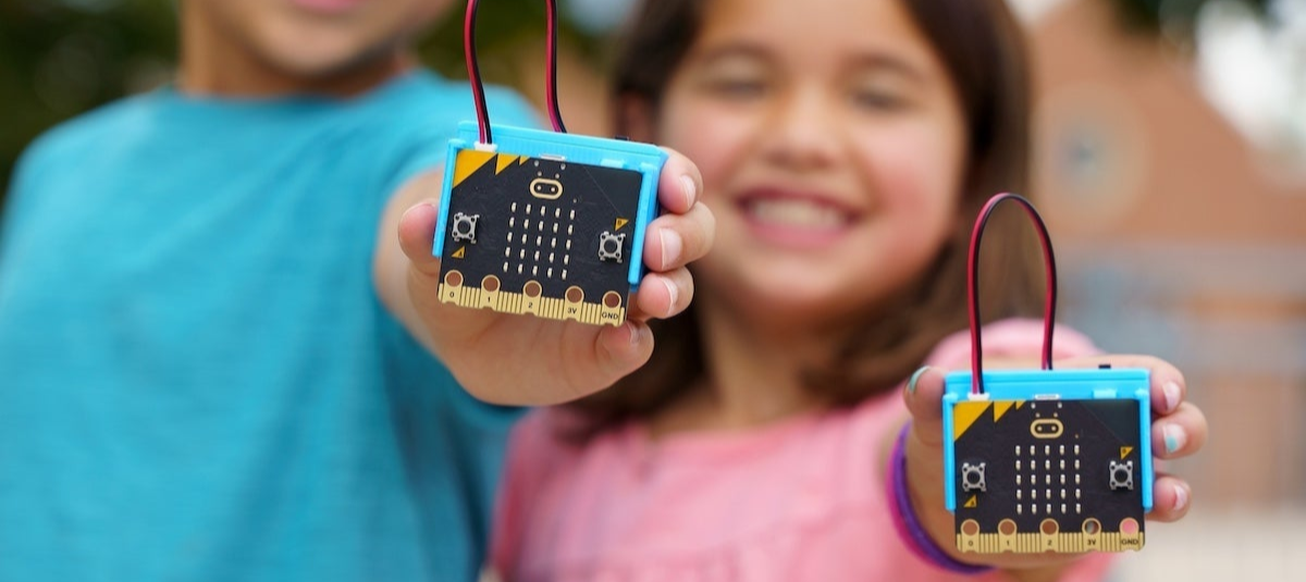 Two children holding micro:bit education boards with colorful cases outdoors | Forward Education