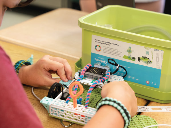 Student hands assembling colorful circuit components on microcontroller with storage bin | Forward Education