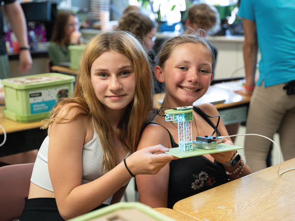 Two students displaying green circuit board projects with electronic components in classroom | Forward Education