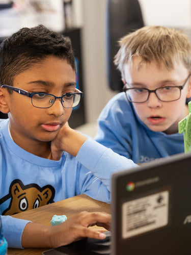 Two students using laptops to build and learn with a wind turbine STEM project kit | Forward Education