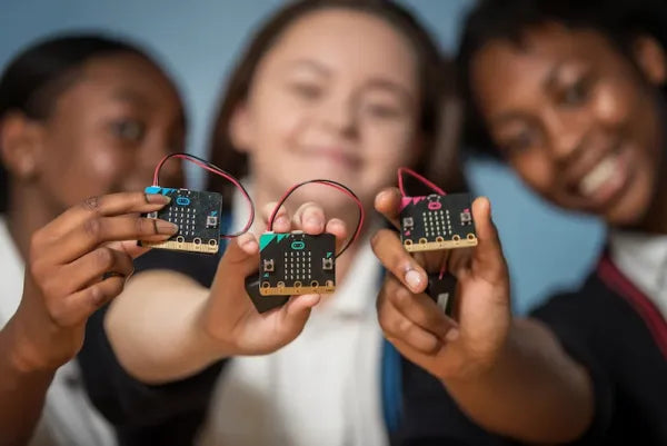 3 students holding micro:bits in different colors